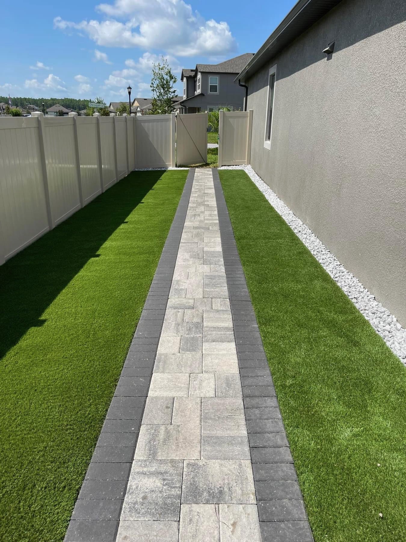 beautiful stone paver pathway by SAMA Landscape Service leading alongside a home to provide elegant and clear movement from the front yard to the backyard.